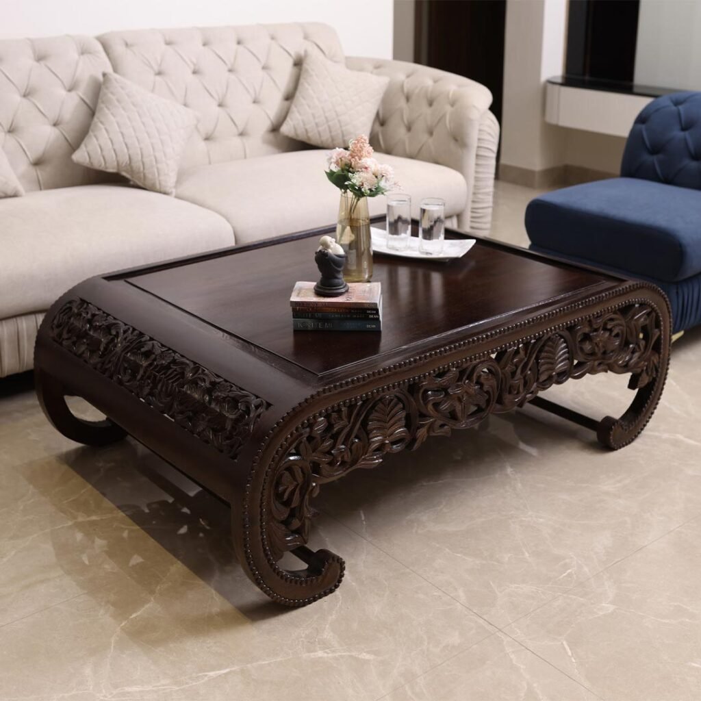 Intricately hand-carved Sheesham wood coffee table with floral patterns and curved edges in walnut brown colour.
