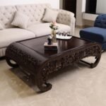 Intricately hand-carved Sheesham wood coffee table with floral patterns and curved edges in walnut brown colour.
