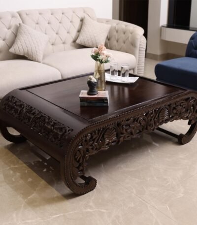 Intricately hand-carved Sheesham wood coffee table with floral patterns and curved edges in walnut brown colour.