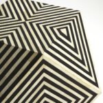 Geometric bone inlay black and white optical illusion side table with bold diamond pattern and hexagonal design.