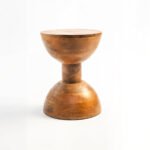 Handcrafted round solid wood side table with natural finish and sculptural hourglass base.