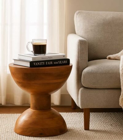 Handcrafted round solid wood side table with natural finish and sculptural hourglass base.