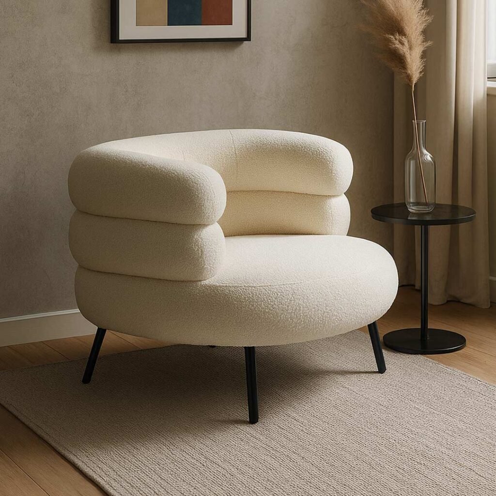 Modern bouclé upholstered armchair with a rounded silhouette and black metal legs.