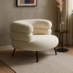Modern bouclé upholstered armchair with a rounded silhouette and black metal legs.