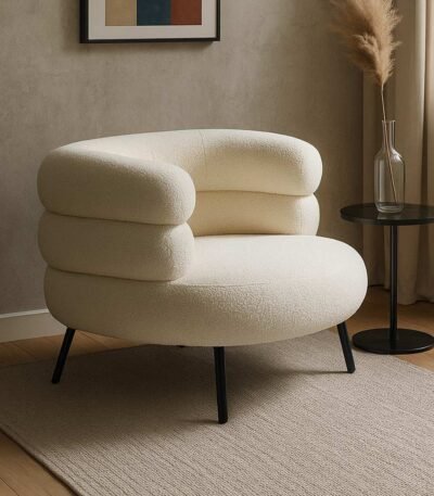 Modern bouclé upholstered armchair with a rounded silhouette and black metal legs.