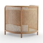 Tejasvi rattan lounge chair with curved cane sides and upholstered seat