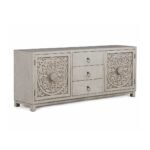 Hand carved TV unit in distressed beige finish crafted from solid mango wood with floral carved cabinet doors and storage drawers.