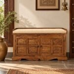 Sheesham Wood Storage Bench with elephant-carved wooden doors, hidden shoe storage and beige cushioned seat in honey finish.