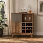 Modern wooden bar cabinet with fluted front detailing, circular metal handle, wine bottle cubbies, and hanging glass holders in a natural finish.