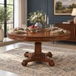 Carvoria Carved Sheesham Dining Table with 148 cm round tabletop, floral carved apron, ornate pedestal base and natural brown finish.