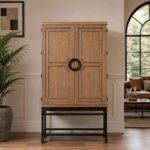 Tall brown bar cabinet with raised panel double doors, circular black handle, and sturdy black metal stand.