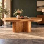 Solstice solid wood oval pedestal dining table in natural finish with sculptural wooden base and spacious 239 cm tabletop.